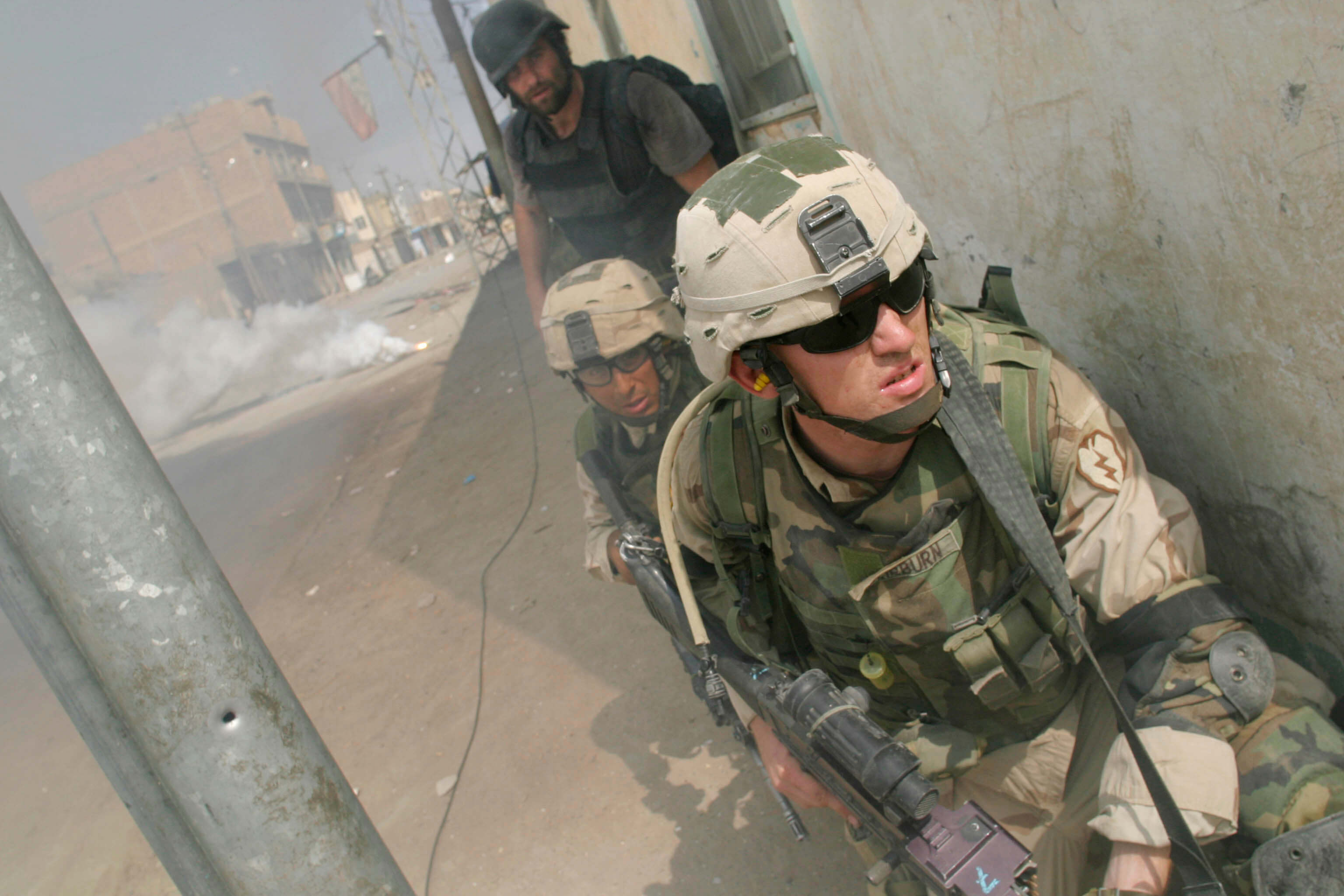 October 1, 2004 - Baquba, Iraq: Time Magazine writer Michael Ware advances with U.S. soldiers with the 25th Infantry Division, 1st battalion, 14th regiment, Alpha Company, 1st Platoon, looks around a corner while a smoke grenade covers his advance during an attack to take back Samarra from insurgent control. The operation circled the city of Samarra with four battalions. After the initial attack the city is to be held with 500 Iraqi National Guard units after the fight. (Max Becherer/Polaris) ///